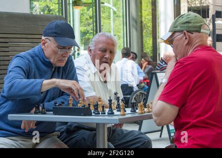 Portland, Oregon USA - 20. April 2015: Drei alte pensionierte Männer spielen eine intensive Partie Schach in einem Park auf einem Tisch im Freien mit einem Timer Stockfoto