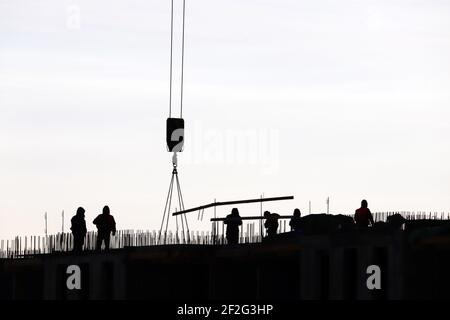 Silhouetten von Arbeitern auf der Baustelle gegen den Himmel. Wohnungsbau, Bauherren arbeiten auf Gerüsten Stockfoto