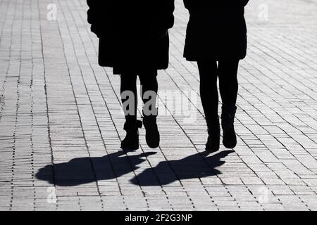 Silhouetten und Schatten zweier Frauen, die die Straße entlang gehen. Konzept der weiblichen Freundschaft Stockfoto