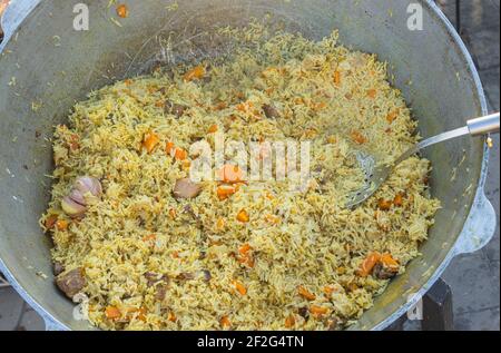 Blick von oben auf den großen Kessel mit klassischem Street Food Pilaf In der Ukraine Stockfoto