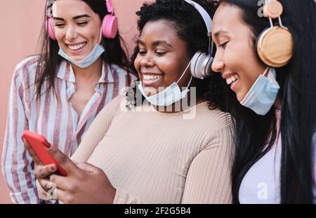 Hispanische junge Frauen haben Spaß zusammen in der Stadt, während Mit Handy - Schwerpunkt auf afrikanische Mädchen Stockfoto