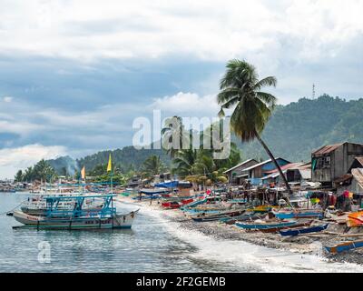 Fischerhäuser und ihre Ausleger Boote am Strand in Kiamba, Provinz Sarangani auf den Philippinen. Stockfoto