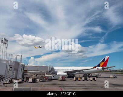 Philippine Airlines Airbus A330 im Terminal 2 des Ninoy Aquino International Airport in Manila, mit Cebu Pacific Airbus A320. Stockfoto