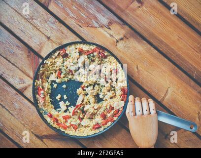 Gejointed hölzerne Schaufensterpuppe Hand hält Griff des Teils gegessen Pfanne von Paella auf hölzernen Deck. Konzept des Lebensstils, mediterrane Küche Stockfoto