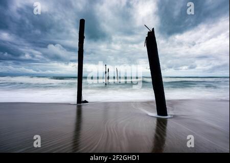 Große Welle trifft eine verfall Holzbrücke am Strand bei stürmischem Wetter am Pilai Strand, Phang nga, Thailand Stockfoto