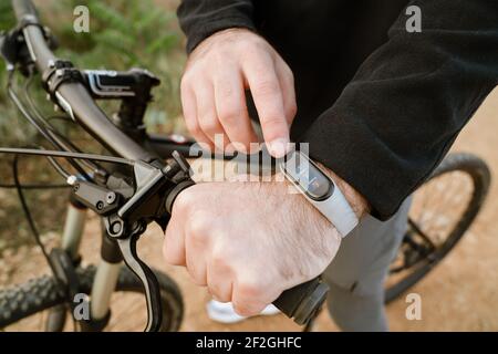 Kaukasischen Kerl mit Smartwatch, während mit Fahrrad fahren im Freien Stockfoto