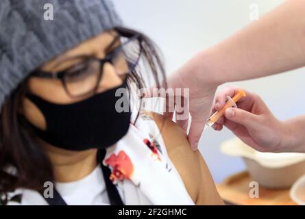 Eine Frau erhält eine Injektion des Coronavirus-Impfstoffs Oxford/AstraZeneca im Elland Road Impfzentrum in Leeds, Wie eine Studie zeigt, sind Menschen aus asiatischen und ethnischen Minderheiten (BAME), die in benachteiligten Gemeinschaften leben, eher zögerlich gegenüber dem Coronavirus-Impfstoff als diejenigen in wohlhabenderen Gebieten. Bilddatum: Freitag, 12. März 2021. Stockfoto