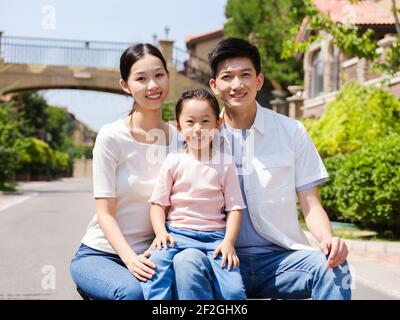 Glückliche Familie von drei in der Outdoor-Gruppe Foto sitzen Und lächelnd Stockfoto