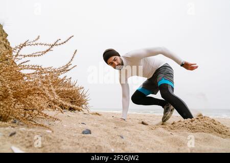 Selbstbewusster junger Sportler, der am Strand trainiert, Krieg, Kleidung trägt Stockfoto