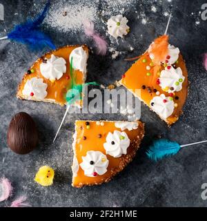Blick in die Höhe von einigen Stücken einer spanischen mona de pascua, einem Kuchen, der am Ostermontag gegessen wird, geschmückt mit einem Schokoladenei, einem Plüschküken und Federn Stockfoto