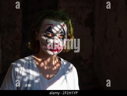 Nahaufnahme Porträt von attraktiven jungen Frau mit Gesichtsfarbe als Joker, Clown gegen schwarzen Hintergrund, Menschen. Stockfoto