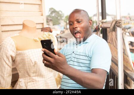 afrikanischer Mann, der glücklich in sein Telefon schaut Stockfoto