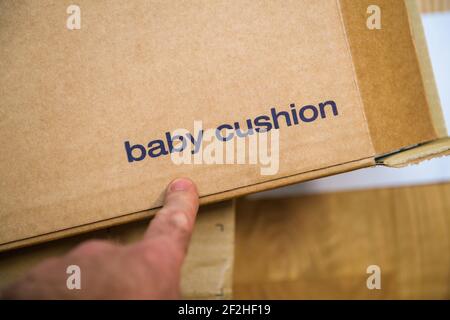 POV männliche Hand hält Finger auf dem Baby Kissen Pappe Karton eines neuen Zustellpakets Stockfoto