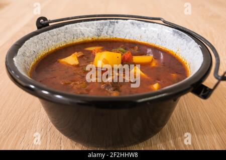 Ungarische Rindergulasch oder Gulyas Suppe oder Eintopf in einem kleinen Kessel mit Kartoffeln, Fleisch, Paprika und Pfeffer serviert Stockfoto