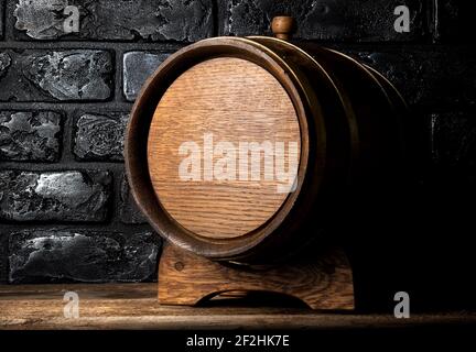 Holzfass auf Tisch in der Nähe von schwarzen Mauer Stockfoto