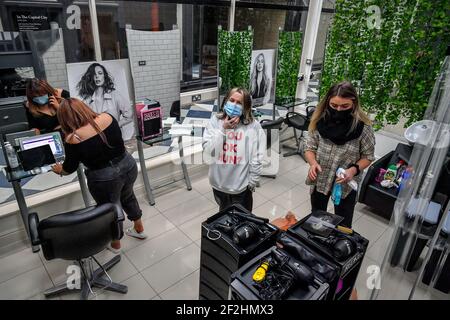 Die Mitarbeiter des Michelle Marshall Salons in Duke St Arcade, Cardiff, reinigen und desinfizieren den Salon, bevor sie ihre Kunden begrüßen, wenn Friseure und Barbiere in Wales ab Montag wieder zu Terminen geöffnet werden können. Bilddatum: Freitag, 12. März 2021. Stockfoto