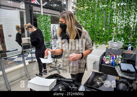 Die Mitarbeiter des Michelle Marshall Salons in Duke St Arcade, Cardiff, reinigen und desinfizieren den Salon, bevor sie ihre Kunden begrüßen, wenn Friseure und Barbiere in Wales ab Montag wieder zu Terminen geöffnet werden können. Bilddatum: Freitag, 12. März 2021. Stockfoto