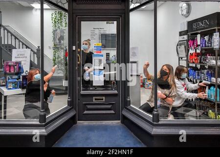 Die Mitarbeiter des Michelle Marshall Salons in Duke St Arcade, Cardiff, reinigen und desinfizieren den Salon, bevor sie ihre Kunden begrüßen, wenn Friseure und Barbiere in Wales ab Montag wieder zu Terminen geöffnet werden können. Bilddatum: Freitag, 12. März 2021. Stockfoto