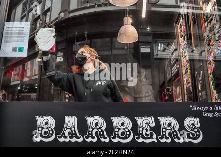 Ein Barbier in Duke St Arcade, Cardiff, wird gereinigt und desinfiziert, bevor er seine Kunden begrüßt, wenn Friseure und Barbiere in Wales ab Montag wieder zu Terminen geöffnet werden können. Bilddatum: Freitag, 12. März 2021. Stockfoto