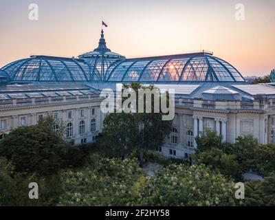 Sonnenaufgang durch Glasdach und Kuppel des Grand Palais of Beaux Arts Architecture (Champs Élysées) in Paris, gekrönt von der französischen Flagge Stockfoto