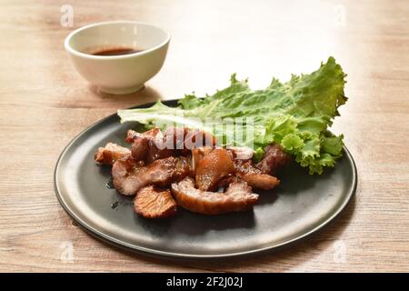 Gegrillter Schweinehals und Ohrstück mit Salat auf dem Teller Dippende würzige Sauce Stockfoto