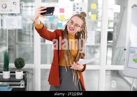 Hipster Frau mit Smartphone für Selfie im Büro Stockfoto
