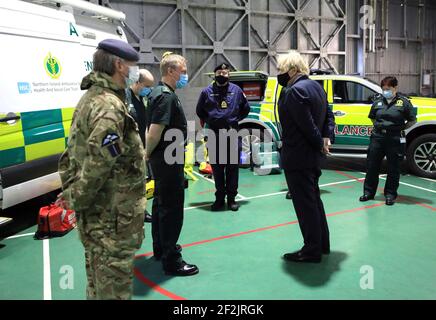 Premierminister Boris Johnson trifft sich mit Mitgliedern des nordirischen Rettungsdienstes und Militärmedizinern während eines Besuchs der Flugstation des Joint Helicopter Command in Aldergrove in Nordirland. Bilddatum: Freitag, 12. März 2021. Stockfoto