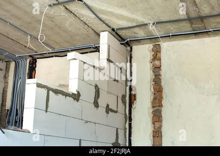 Elektrokabel in einer Schutzwellung an der Decke und an der Wand in einem Raum, in dem Bauarbeiten durchgeführt werden. Stockfoto