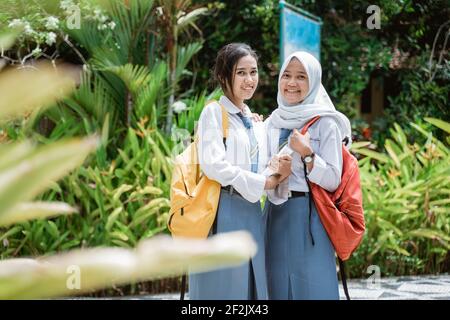 Zwei indonesische High School Mädchen tragen Schultaschen und lächeln An die Kamera Stockfoto