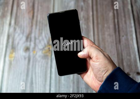 Ein Mobiltelefon oder Mobiltelefon, das in einem gehalten wird Hand mit der ZIEGE App auf dem Bildschirm geöffnet Stockfoto