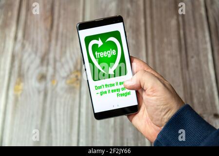 Ein Mobiltelefon oder Mobiltelefon, das in einem gehalten wird Hand mit der Freegle App auf dem Bildschirm geöffnet Stockfoto