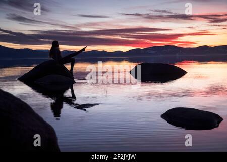 Junge abenteuerliche Frauen sitzen auf Felsen und plätschern Wasser Lake Tahoe Stockfoto