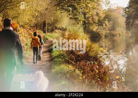 Familie zu Fuß entlang Weg durch Kanal im Herbst Stockfoto