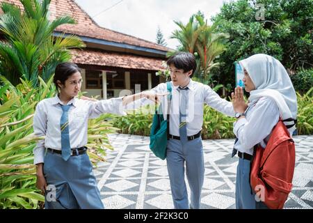 Zwei Mädchen der High School stritten sich mit der Hand Gesten und ein schöner männlicher Schüler trennten sich Stockfoto