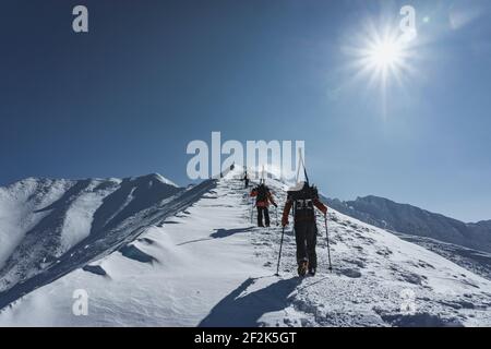 Menschen mit Skistöcken Klettern schneebedeckten Berg gegen Himmel während Urlaub Stockfoto