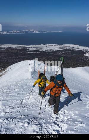 Menschen mit Skistöcken klettern schneebedeckten Berg während des Urlaubs Stockfoto