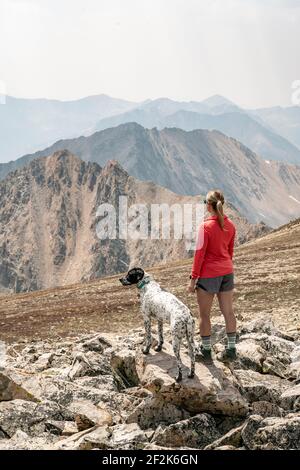 Rückansicht der Hikerin mit Hund auf Berg gegen Himmel im Urlaub Stockfoto