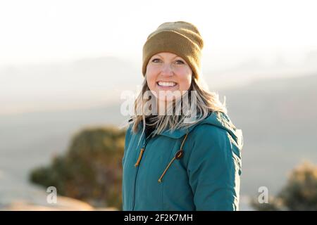 Porträt einer lächelnden Frau in warmer Kleidung in der Wüste während Urlaub Stockfoto