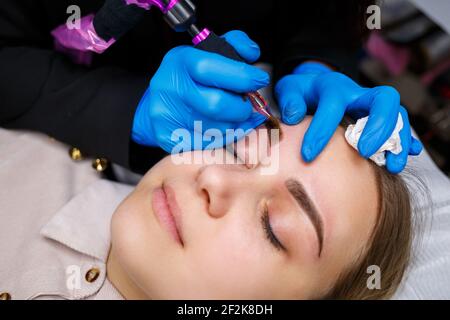 Gesicht einer schönen Frau mit buschigen Augenbrauen in einem Schönheitssalon. Dauerhafte Make-up für Augenbrauen. Kosmetikerin macht Augenbraue Tattoo für Frauen. Beauty-Prozess Stockfoto