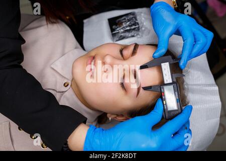Frau mit Permanent Make-up Tattoo auf ihren Augenbrauen. Nahaufnahme Kosmetikerin macht eine Skizze der Augenbrauen. Professionelles Make-up und kosmetische Hautpflege. Stockfoto