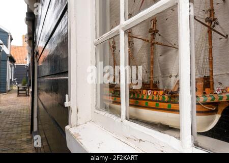 Nahaufnahme des kleinen marinen weißen Schiffs-Modells aus dem Holz auf einer Fensterbank im traditionellen Holzhaus in Marken, Niederlande Stockfoto