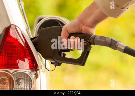 Horizontaler Schuss einer Menschenhand, die Gas in ein Auto pumpt. Stockfoto