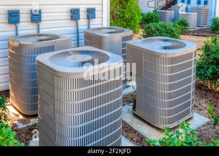 Horizontale Aufnahme von vier Klimaanlagen außerhalb eines gehobenen Apartmentkomplexes. Stockfoto