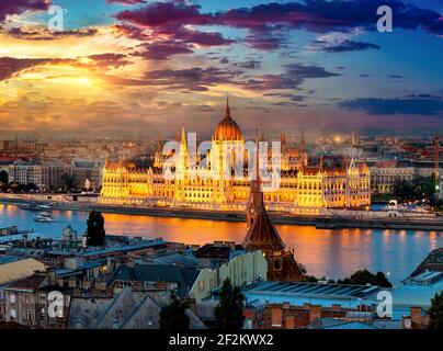 Ungarisches Parlament am Ufer der Donau beleuchtet am Abend, Budapest