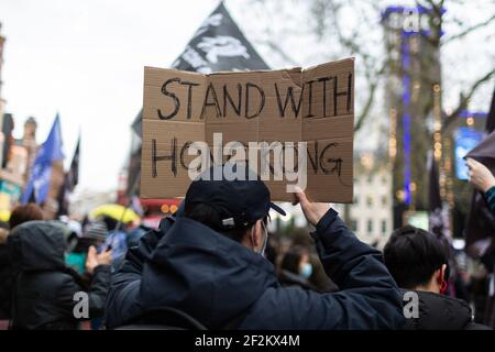 Protestant mit Plakat "Stand with Hong Kong", bei Demonstration gegen die Kommunistische Partei Chinas, Leicester Square, London, 12. Dezember 2020 Stockfoto