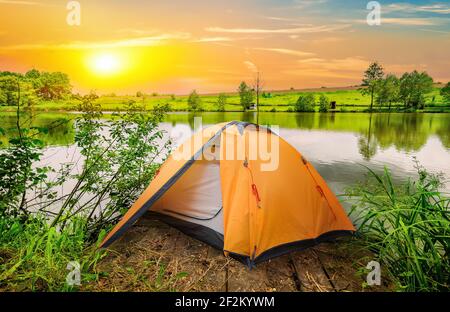 Zelt und ruhiger Fluss am Morgen Stockfoto