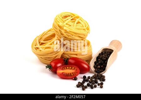 Rohe Spaghetti-Nester, Tomaten und Pepr-Körner auf weißem Hintergrund Stockfoto