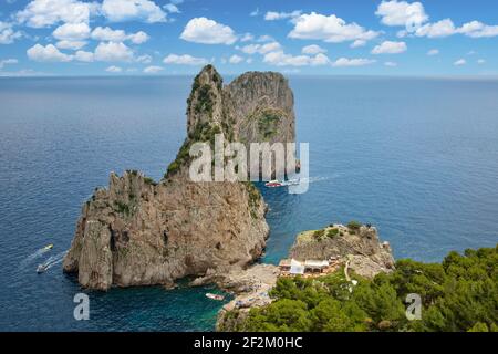 Blick auf ein Restaurant und felsigen Strand zwischen Faraglioni Klippen. Blick auf die berühmten Faraglioni Felsen im blauen Tyrrhenischen Meer, Capri Insel, Italien Stockfoto