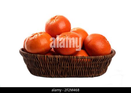 Ganze saftige frische Orangenfrüchte in einem Weidenkorb auf Ein weißer Hintergrund Stockfoto