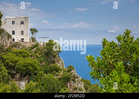 Traditionelles italienisches Haus auf einer Klippe gelegen. Landschaftsansicht mit Bäumen und Klippen und einem fantastischen Blick auf das Tyrrhenische Meer auf der Insel Capri, Italien Stockfoto